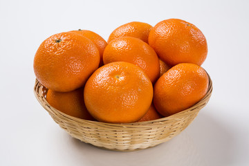 Some tangerines in a basket over a wooden surface