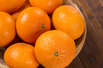 Some tangerines in a basket over a wooden surface