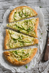 pizza with zucchini, onions and mozzarella on a light wooden background