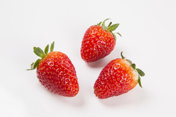 A strawberry cut in a half in front of three entire strawberries
