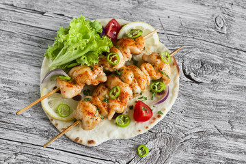 Fototapeta na wymiar chicken kebab and fresh vegetables on a homemade tortilla on a light wooden background