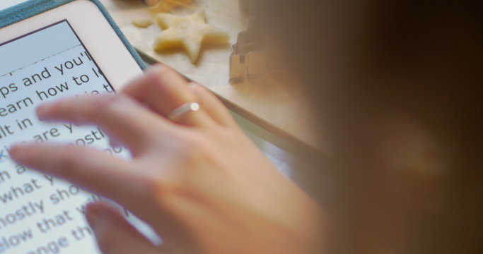 Woman making cookies using recipe on pad