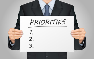 businessman holding priorities word poster