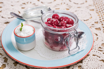 Raspberry dessert. raspberries in small glass jar and whipped cream in a cup
