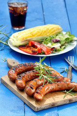 Grilled sausage and vegetables on a blue wooden background in th