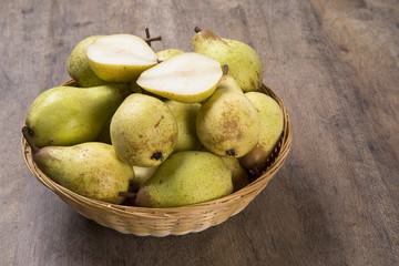 Some pears in a basket over a wooden surface seen from above