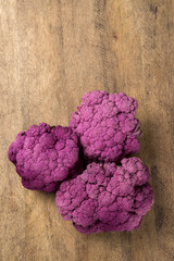 Some purple cauliflowers over a wooden surface seen from above
