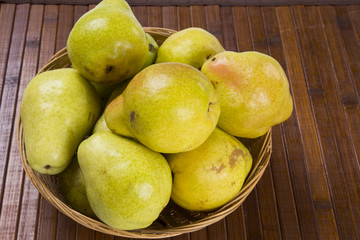 Some pears in a basket over a wooden surface seen from above