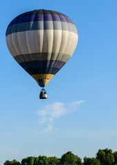 hot air balloon in blue sky over the trees