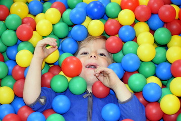 Fototapeta na wymiar Cute little boy plays in ball pool (Bällebad)