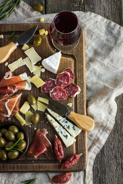 Assortment of various types of cheese and meat on wooden board