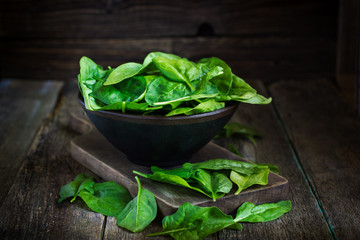 Fresh spinach in bowl on wooden background