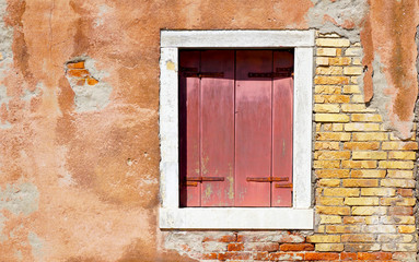 red window in white frame and ancient decay wall