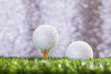 Golf ball on a tee peg and Golf ball on grass, bokeh background silver.