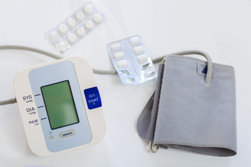 Close up of a digital blood pressure monitor and medications