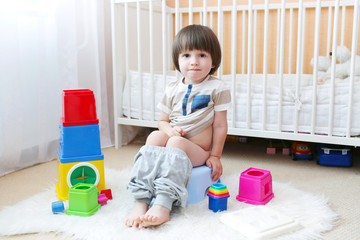 Lovely little boy sitting on potty at home