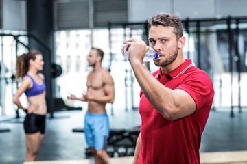 Fototapeta na wymiar Attentive muscular trainer drinking water