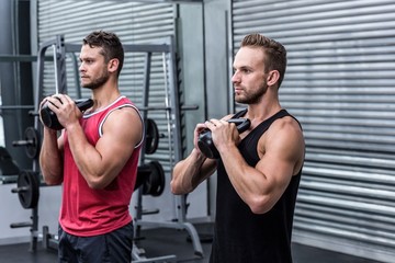 Naklejka premium Muscular men exercising with kettlebells