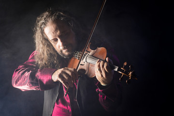 handsome man playing classical violin through blue smoke