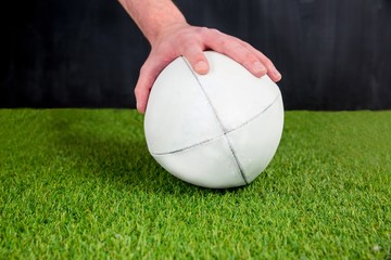 A rugby player posing a rugby ball