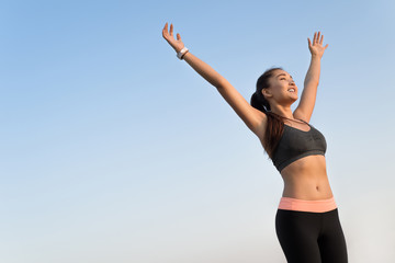 Happy asian woman raising arms to the sky.