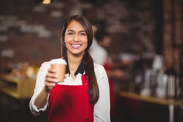 Smiling waitress handing a take-away mug