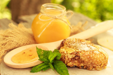 Honey in jar with honeycomb and wooden background.