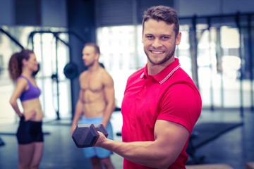 Fototapeta na wymiar Muscular trainer lifting a dumbbell 