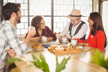 Laughing friends enjoying coffee and treats