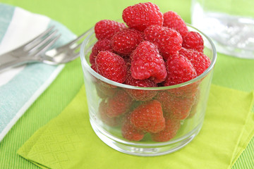 Himbeeren in Schale aus Glas mit grüner Serviette und Besteck - Beeren naschen
