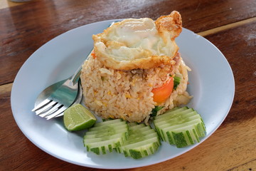 Fried rice and fried eggs on top with decorate slice cucumber and lime ( rear view )