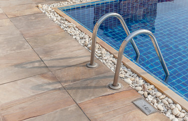 Grab bars ladder in the clear blue swimming pool.