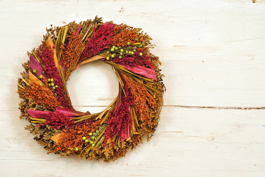A wreath of dried in fall colors flowers on wooden wall