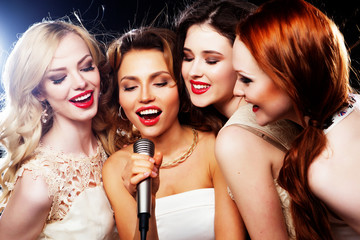 Four beautiful stylish girls singing karaoke  - obrazy, fototapety, plakaty