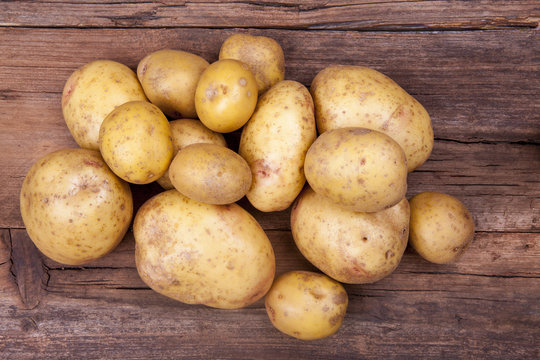 Potatoes bunch shot cropped on a wooden background from above 