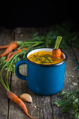 carrot  soup in blue mug on rustic background