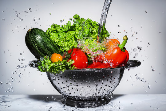 Fototapeta vegetables in a colander under running water