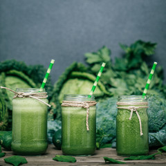 Blended green smoothie with ingredients on wooden table