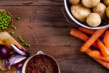 Sheperds pie ingredients shot on a wooden background from above