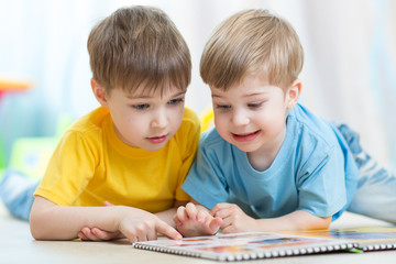 children read together book lying on floor in nursery