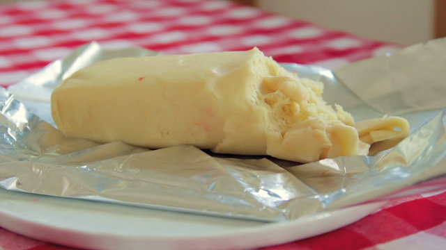 Woman lays with her hand a white plate with white marzipan lump on the table.
Close up shot.