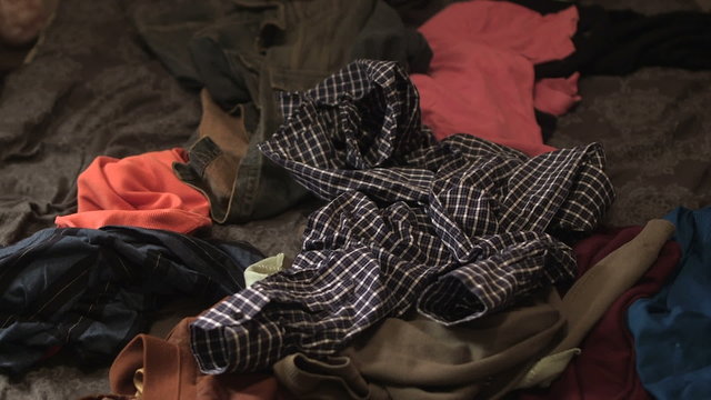 Clothes thrown on a pile of clothes in bed.