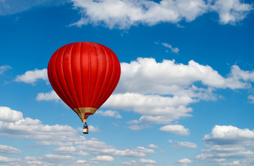 Red hot air balloon in blue cloudy sky