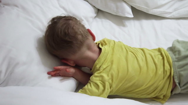 Little boy asleep, rolls over in his sleep

