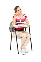 Pensive female student sitting on a school desk
