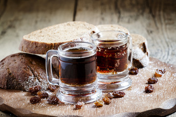 Traditional Russian drink kvass in a mug, with rye bread on a wo