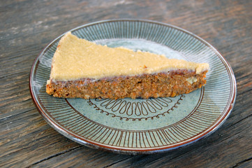 slice of raw vegan carrot cake with cashew cream on rustic wooden table