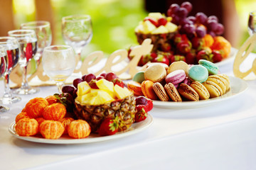 Closeup image of fresh fruits and berries and cookies at table