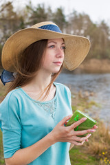 Fototapeta premium Freckled girl in hat standing with note and looking away