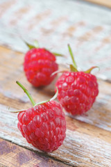 Three red rasberry on old vintage wooden table.